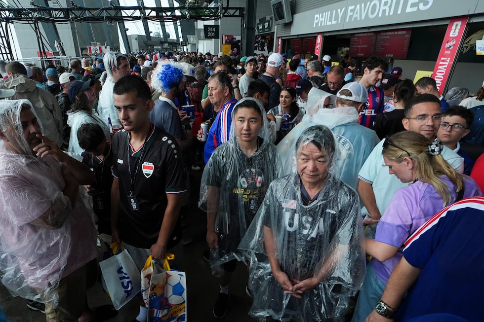 Fans wait in a sheltered area of the stadium as bad weather halts play during the World Cup...